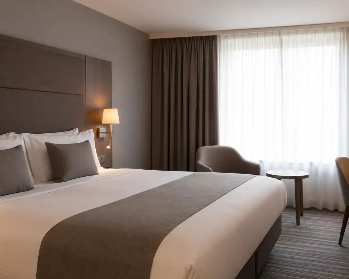 Chambre d’hôtel moderne avec lit double, bureau et lumière naturelle
